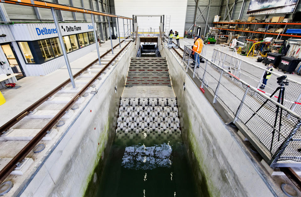 This photo taken in Jan. 2019 and made available by Deltares shows the flume wave tank in Delft, Netherlands, that is used to test structure designs for the strengthening work for the Afsluitdijk. With climate change bringing bigger storms and rising sea levels, one of the low-lying Netherlands’ key defenses against the sea is getting a major makeover. The 5-year project will see workers lay thousands of concrete blocks and raise parts of the 87-year-old Afsluititdijk dike. (Guus Schoonewille/Deltares via AP)