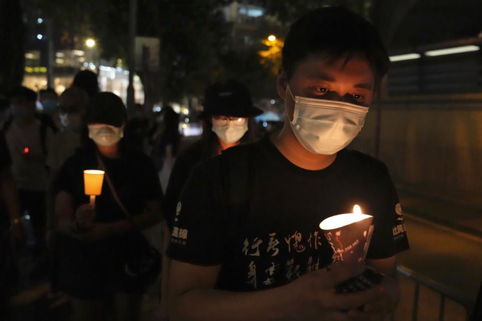 FILE - People walk with candles to mark the anniversary of the military crackdown on a pro-democracy student movement in Beijing, outside Victoria Park in Hong Kong, Friday, June 4, 2021. For Hong Kong’s pro-democracy movement, 2021 has been a year in which the city’s authorities and the central government in Beijing stamped out nearly everything it had stood for. (AP Photo/Kin Cheung, File)