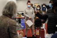 Leah Perkins, of Worcester, Mass., center, stands in line to receive a booster shot of the Pfizer COVID-19 vaccine, Thursday, Dec. 2, 2021, at a mobile vaccination clinic, in Worcester. As the U.S. recorded its first confirmed case of the omicron variant, doctors across the country are experiencing a more imminent crisis with a delta variant that is sending record numbers of people to the hospital in New England and the Midwest. (AP Photo/Steven Senne)