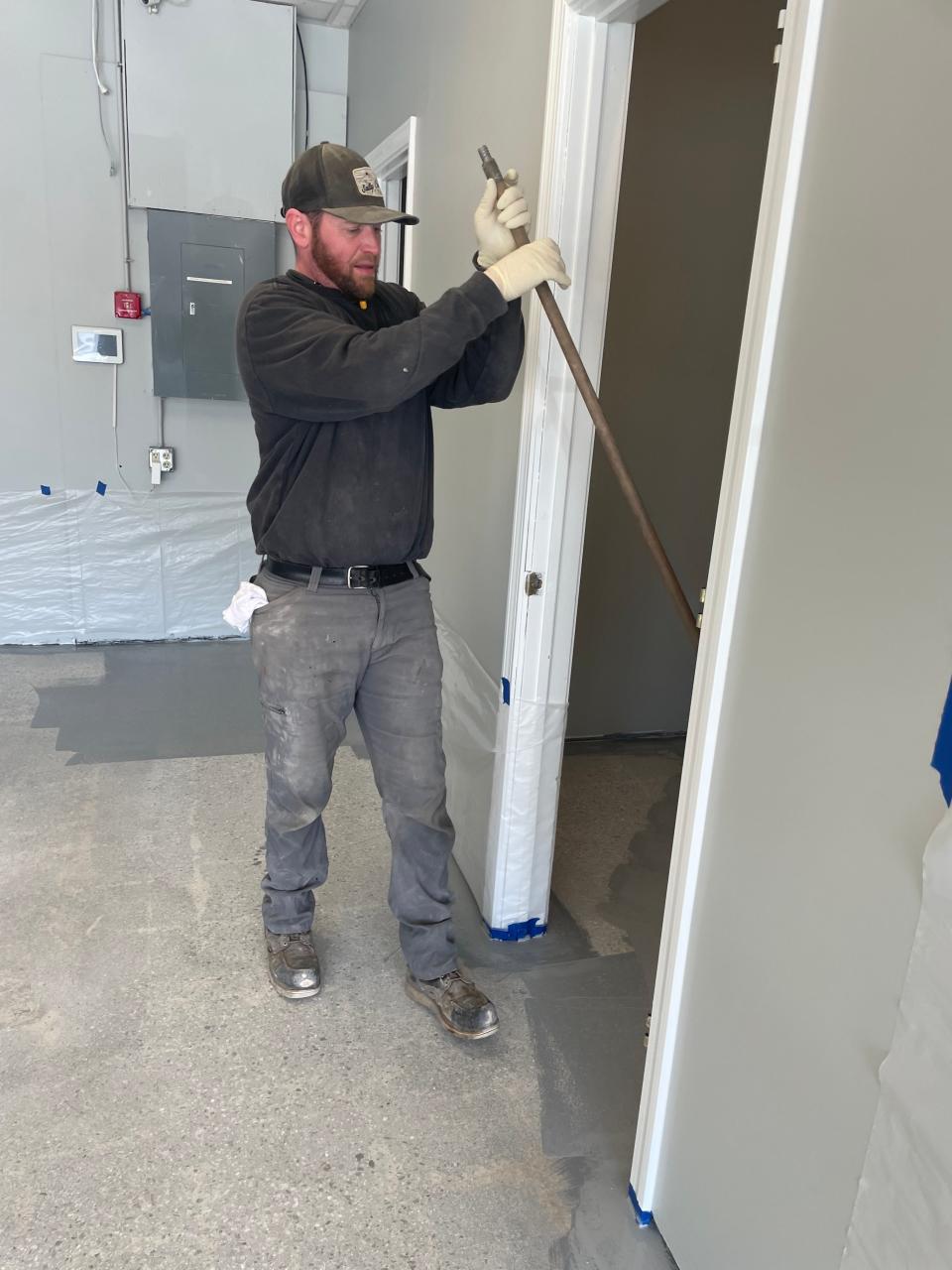 Collin Bowns of Concrete Floors Company LLC in Plainfield is applying the base coat for epoxy flooring inside Small Potatoes at the Yantic River Plaza. Small Potatoes is one of 11 businesses to receive a flood relief micro grant on Tuesday.