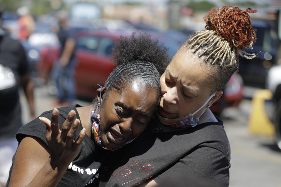 Two women pray, Tuesday, June 2, 2020, in Louisville, Ky., near the intersection where David McAtee was killed Sunday evening. Louisville police say video obtained from security cameras at McAtee’s business and an adjoining business show that McAtee fired a gun as police and National Guard soldiers were enforcing a curfew approached his business. (AP Photo/Darron Cummings)