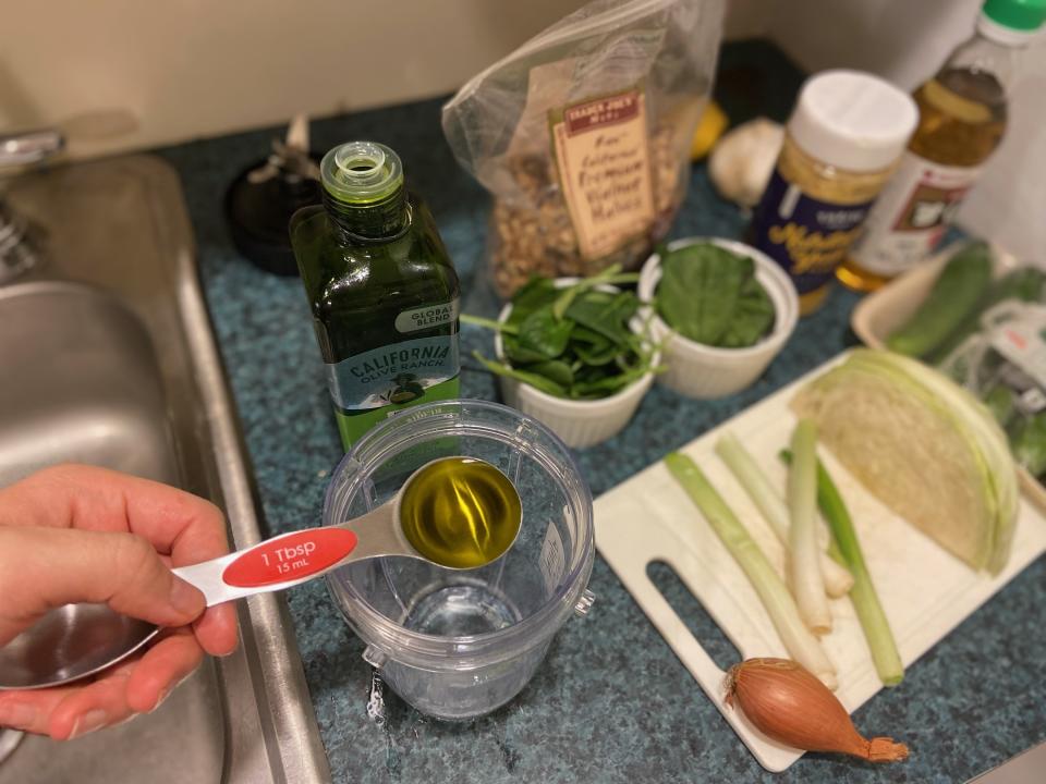 Jen holding a measuring table spoon of olive oil