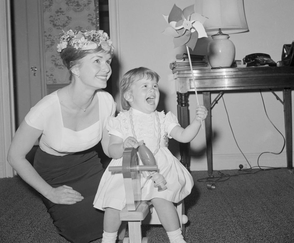 Debbie Reynolds is interviewed in her hotel room while 2-year-old Carrie squeals with delight and brandishes a pinwheel.