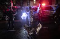 A woman walks her dog past police officers securing a scene where protesters were arrested for breaking a curfew during a solidarity rally calling for justice over the death of George Floyd, Friday, June 5, 2020, in the Brooklyn borough of New York. Floyd, an African American man, died on May 25 after a white Minneapolis police officer pressed a knee into his neck for several minutes even after he stopped moving and pleading for air. (AP Photo/Wong Maye-E)