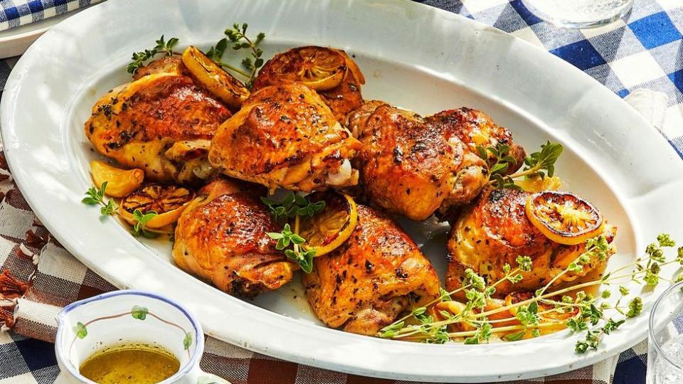 fall recipes lemony chicken thighs arranged in an oval serving platter with thyme and lemon slices