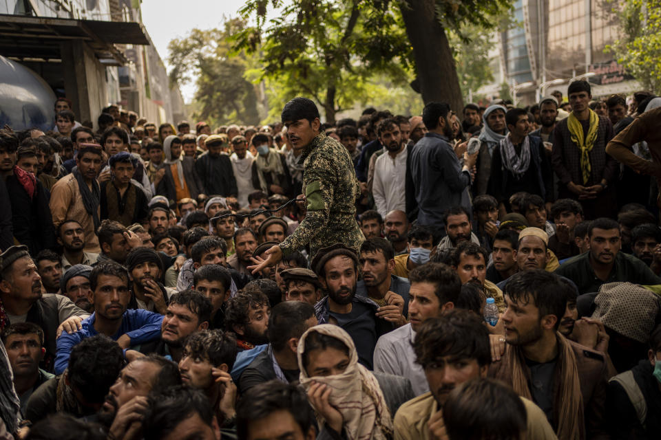 Afghans wait in front of a bank branch as they try to withdraw money in Kabul, Afghanistan, Sunday, Sept. 12, 2021. (AP Photo/Bernat Armangue)