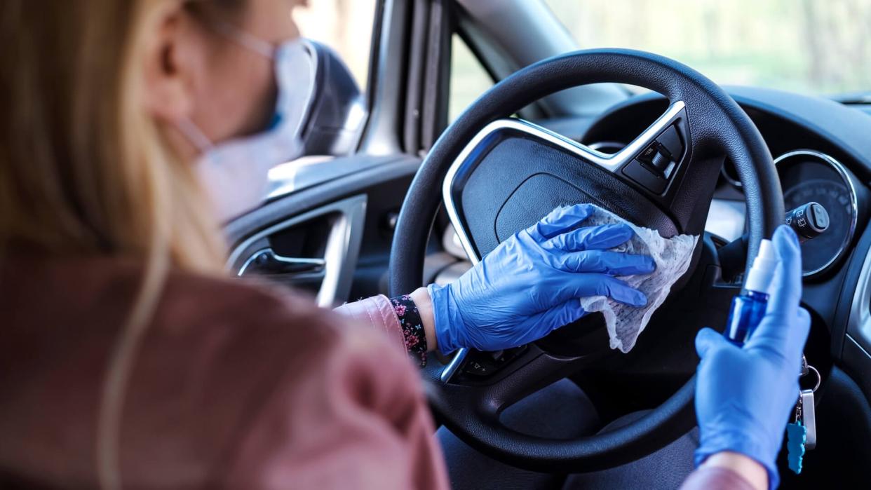 Woman in the car with protective glove and facial mask.