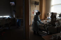 Chaplain Anne Dauchy holds the hand of a dying COVID-19 patient after the sacrament of anointing of the sick administered over the phone by a priest of at Providence Holy Cross Medical Center in the Mission Hills section of Los Angeles on Saturday, Jan. 9, 2021. (AP Photo/Jae C. Hong)