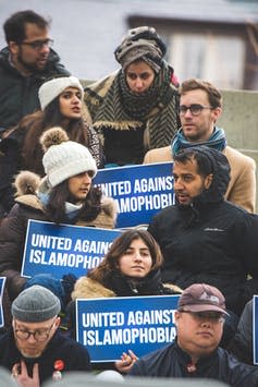 People hold signs reading, 'United against Islamophobia.'