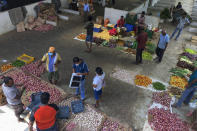 People purchase imported onions and garlic at a market in Colombo, Sri Lanka, Sunday, June 26, 2022. Sri Lankans have endured months of shortages of food, fuel and other necessities due to the country's dwindling foreign exchange reserves and mounting debt, worsened by the pandemic and other longer term troubles. (AP Photo/Eranga Jayawardena)