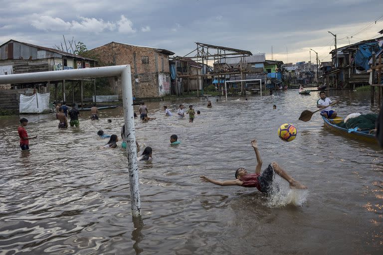 Un niño patea una pelota en un área inundada de la comunidad de Belén en Iquitos, Perú, el 20 de marzo 
