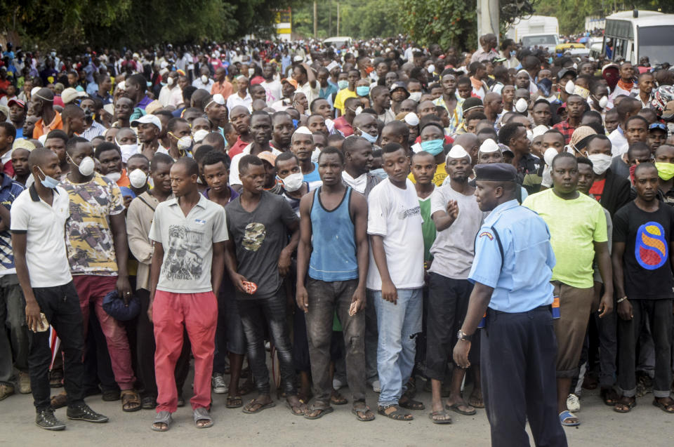 Kenyan police hold back ferry passengers after new measures aimed at halting the spread of the new coronavirus instead caused a crowd to form outside the ferry in Mombasa, Kenya Friday, March 27, 2020. The new measures required public transport vehicles to drop passengers 1km away and walk to the ferry terminal and then queue, but passengers fearing they would get stuck before a 7pm curfew started crowding to get on causing police to fire tear gas and round up the passengers. (AP Photo)