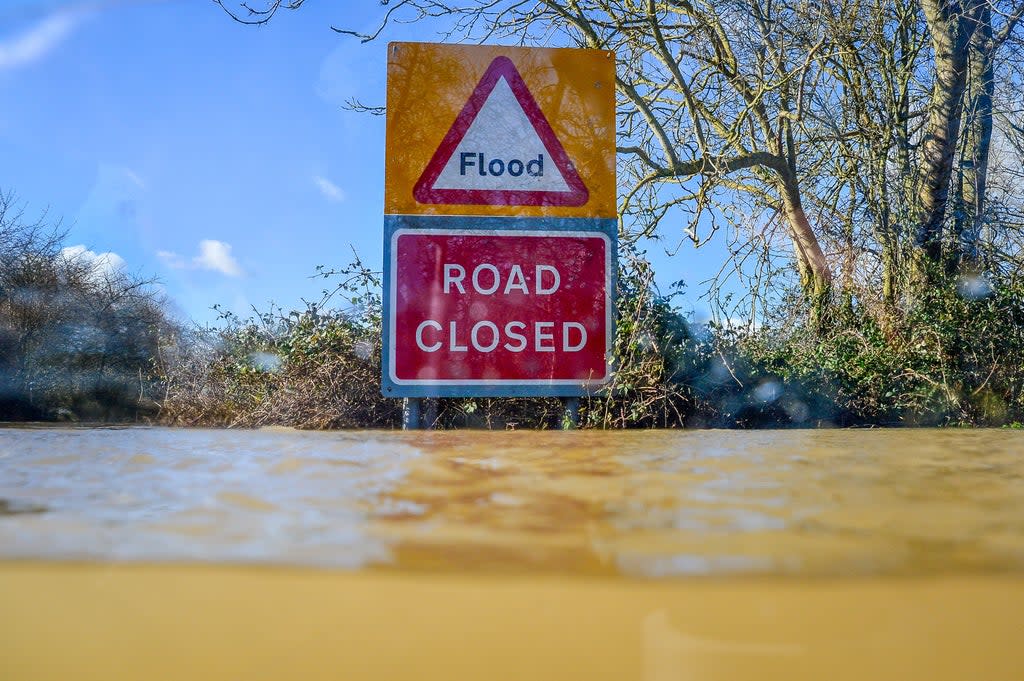 A road closed sign pokes out above floodwater (Ben Birchall/PA) (PA Archive)