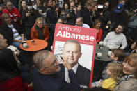 Australia's Prime Minister-elect Anthony Albanese, center, signs a poster for twin brothers Dimitri and Stavros, bottom right, as he visits a coffee shop in suburban Marrickville, Sydney, Sunday, May 22, 2022. Albanese has promised to rehabilitate Australia's international reputation as a climate change laggard with steeper cuts to greenhouse gas emissions. (Dean Lewins/AAP Image via AP)