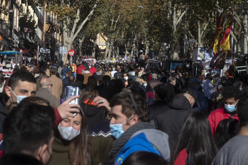 People enter the Rastro flea market in Madrid, Spain, Sunday, Nov. 22, 2020. Madrid's ancient and emblematic Rastro flea market reopened Sunday after a contentious eight-month closure because of the COVID-19 pandemic that has walloped the Spanish capital. (AP Photo/Paul White)