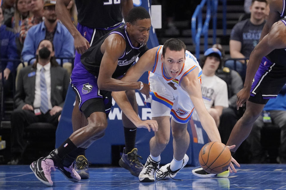 Oklahoma City Thunder center Aleksej Pokusevski, right, reaches for the ball in front of Sacramento Kings guard De'Aaron Fox, left, in the first half of an NBA basketball game Monday, Feb. 28, 2022, in Oklahoma City. (AP Photo/Sue Ogrocki)