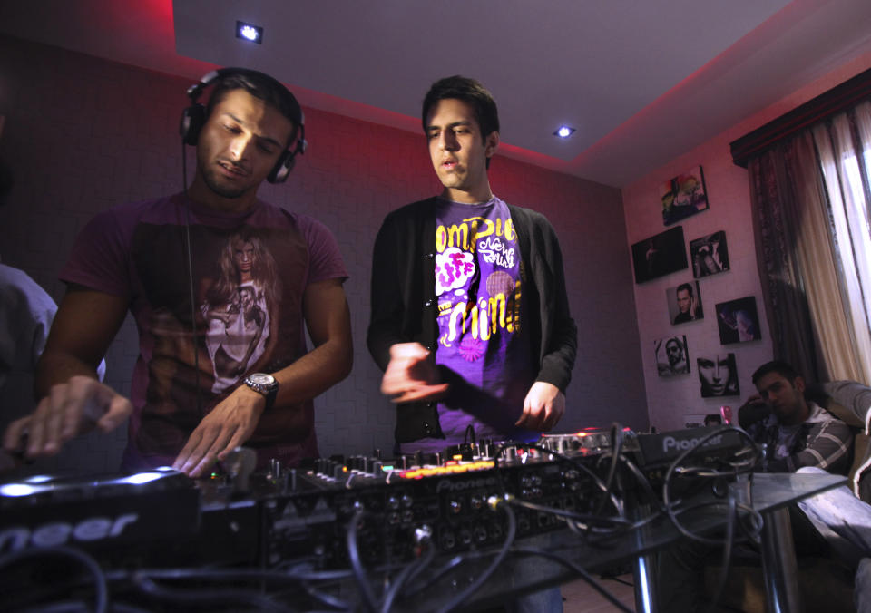 In this picture taken on Wednesday, Feb. 13, 2013, Iranian musicians Pedram, left, and Soheil, members of a band called "Rebeat," compose remixes of folk songs on their electronic mixing console in Tehran, Iran. Headphone-wearing disc jockeys mixing beats. It’s an underground music scene that is flourishing in Iran, despite government restrictions. (AP Photo/Vahid Salemi)