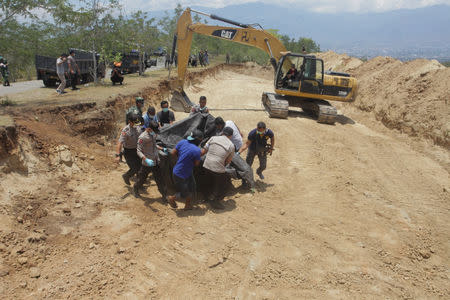 Indonesian security forces carry the body of a victim of the earthquake and tsunami into a mass grave in Palu, Central Sulawesi, Indonesia October 1, 2018 in this photo taken by Antara Foto. Antara Foto/Muhammad Adimaja/ via REUTERS