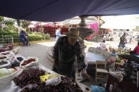 Vendor Salvador Avila tends to his dried chilies in the Indigenous township of Cheran, Michoacan state, Mexico, Tuesday, Jan. 18, 2022. Avila, 65, remembers how it was before Cheran began its experiment in self-rule in 2011 by blocking roads used by illegal loggers. He was scared off his land by threats from loggers, who then clear-cut his land. “The last threat was that if we showed up there (at his land) again, they were going to kidnap us, we were going to be found in bags,” Avila said. “Several people were killed and they were found in pieces, burned.” (AP Photo/Fernando Llano)