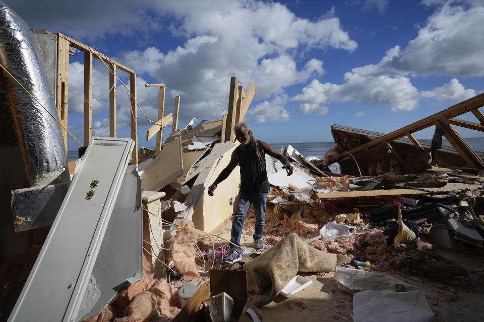 FILE - Family friend Tony McDavid walks through the wreckage of the beachfront home of Nina Lavigna, as friends help recover salvageable belongings after half of her house collapsed following beach erosion from Hurricane Nicole, Nov. 12, 2022, in Wilbur-By-The-Sea, Fla. A major new United Nations report being released Monday, March 20, 2023, is expected to provide a sobering reminder that time is running out if humanity wants to avoid passing a dangerous global warming threshold. (AP Photo/Rebecca Blackwell, File)