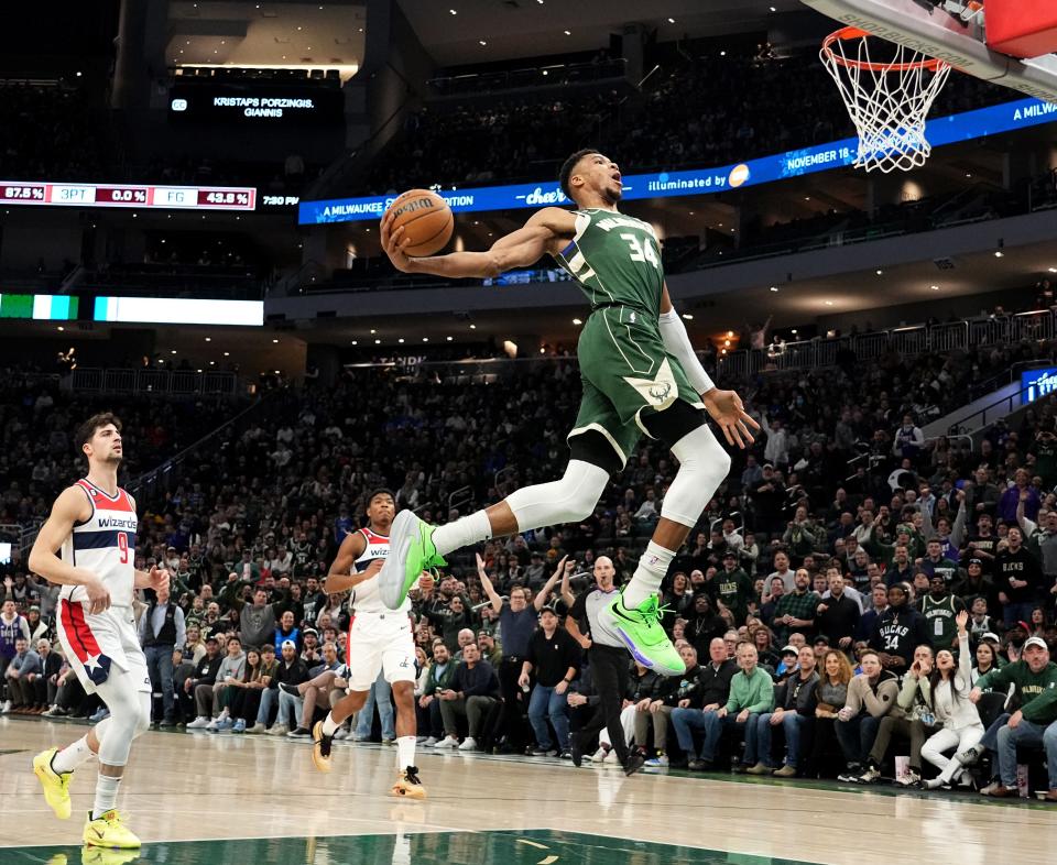 Milwaukee Bucks forward Giannis Antetokounmpo (34) throws down a dunk as Washington Wizards forward Deni Avdija (9) looks on during the first half of their game  January 3, 2023 at Fiserv Forum in Milwaukee.