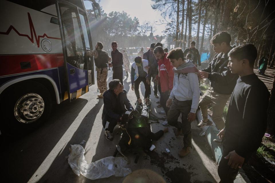 People gather around a stretcher with an injured person lying on it.