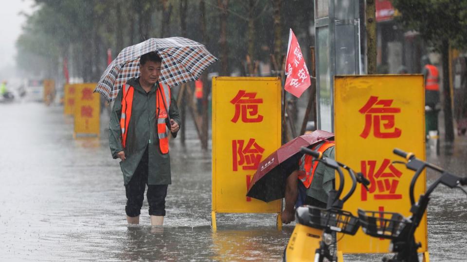 Mitarbeiter stellen Warnschilder auf mit der Aufschrift «Gefahr!» in einem überschwemmten Gebiet im Kreis Wuzhi in der zentralchinesischen Provinz Henan.