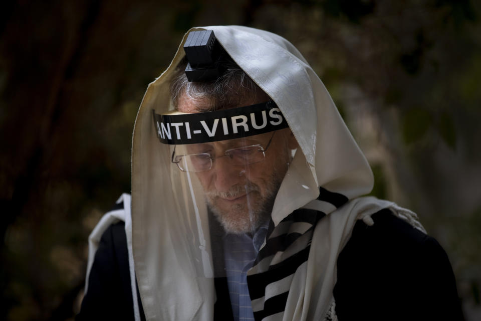 An Ultra-Orthodox Jewish man wears a face mask during a morning prayer next to his house as synagogues are limited to twenty people during a nationwide three-week lockdown to curb the spread of the coronavirus, in Bnei Brak, Israel, Thursday, Sept 24, 2020. Israel moved to further tighten its second countrywide lockdown as coronavirus cases continued to soar. The Cabinet voted to close all nonessential businesses, including open-air markets. Prayers and political demonstrations would be limited to open spaces and no more than 20 people, and participants would not be able to travel more than a kilometer (0.6 miles) from home for either. (AP Photo/Oded Balilty)