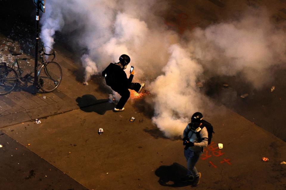 A protester kicks back a tear gas canister as clashes occur on the sidelines of an election night following the second round results of France’s legislative election at Republique Square in Paris on the night of 8 July 2024 (AFP via Getty Images)