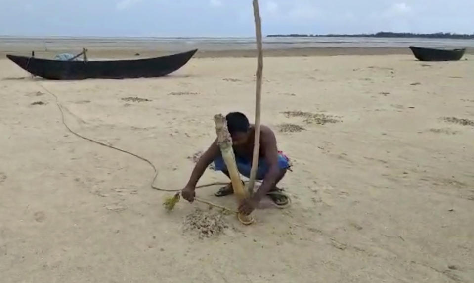 In this Wednesday, May 20, 2020, frame grab from video, a fisherman anchors his boat before Cyclone Amphan made landfall, at Baguranjalpai village in East Midnapore district in West Bengal state, India. People forgot about social distancing and crammed themselves into government shelters, minutes before Cyclone Amphan crashed in West Bengal. The cyclone killed dozens of people and the coronavirus nine in this region, one of India’s poorer states. Even before the cyclone, its pandemic response was lagging; the state has one of the highest fatality rates from COVID-19 in India. With an economy crippled by India’s eight-week lockdown, and health care systems sapped by the virus, authorities must tackle both COVID-19 and the cyclone’s aftermath.(Debasis Shyamal via AP)