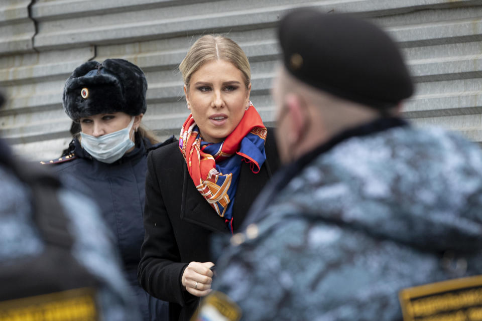 Russian opposition activist Lyubov Sobol, center, walks to the court escorted by police and Russian Federal Bailiffs service officers in Moscow, Russia, Monday April 5, 2021. A Moscow court will start considering the case against Navalny ally Lyubov Sobol, who is charged with unlawful entry into a dwelling. In December Sobol rang the doorbell of a flat of a relative of an alleged FSB agent Konstantin Kudryavtsev, whom Navalny accused of his poisoning. (AP Photo/Pavel Golovkin)