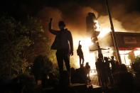 FILE - In this May 29, 2020, file photo, protesters gather in front of a burning fast-food restaurant in Minneapolis. Reports of hateful and violent speech on Facebook poured in on the night of May 28 after President Donald Trump hit send on a social media post warning that looters who joined protests following Floyd's death last year would be shot, according to internal Facebook documents shared with The Associated Press. (AP Photo/John Minchillo, File)