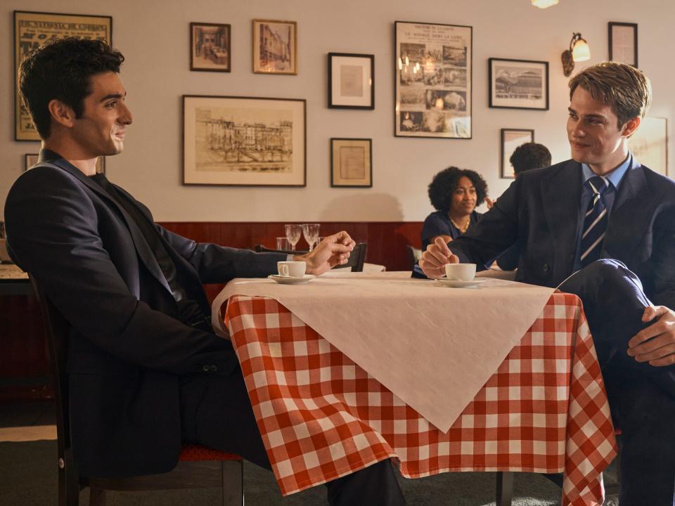 alex and henry in red white and royal blue, sitting together at a table wearing suits