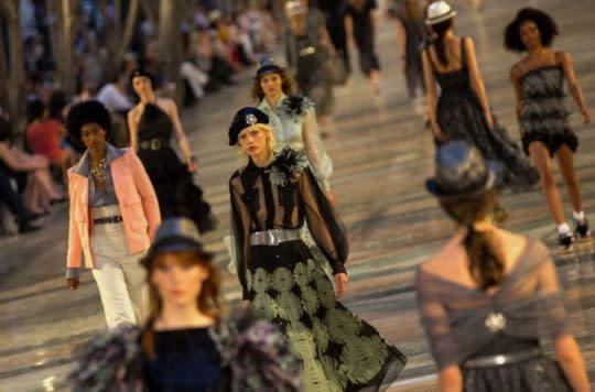 A model in a green and black ensemble and sequin beret makes her way down the runway. (Photo: AP)