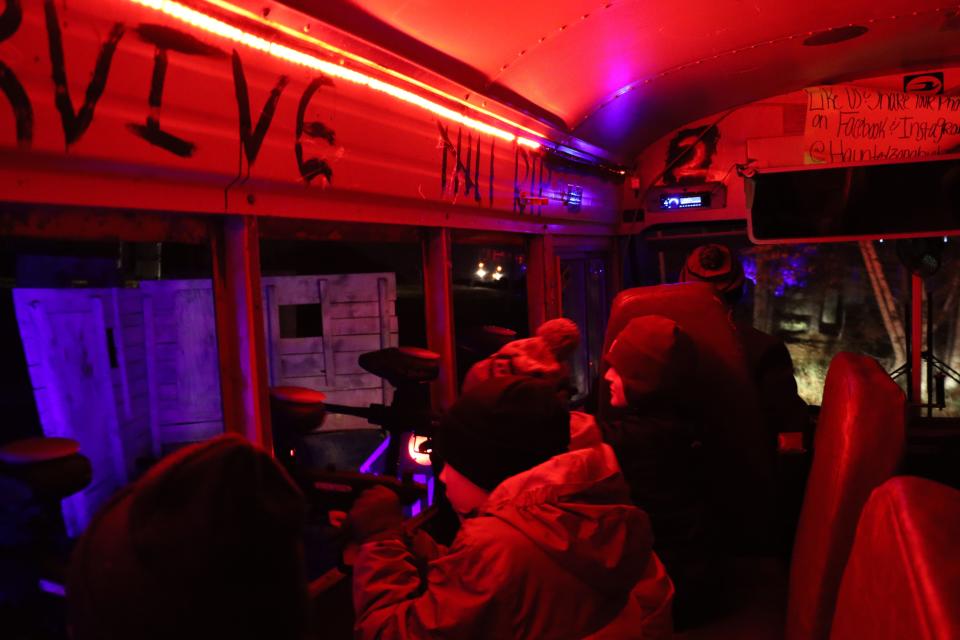 Zombie hunters shoot paintball guns during a Halloween-themed outing at Commando Paintball in Abrams. The hunters ride a school bus, named “Zombus,” through a 32-acre paintball site.