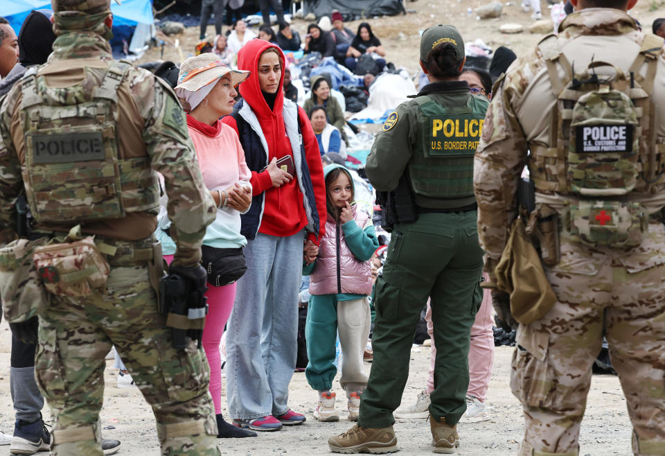 Federal law enforcement agents and officers keep watch as immigrants are lined up to be transported from a makeshift camp between border walls between the U.S. and Mexico on May 13, 2023, in San Diego, California.  / Credit: Getty Images