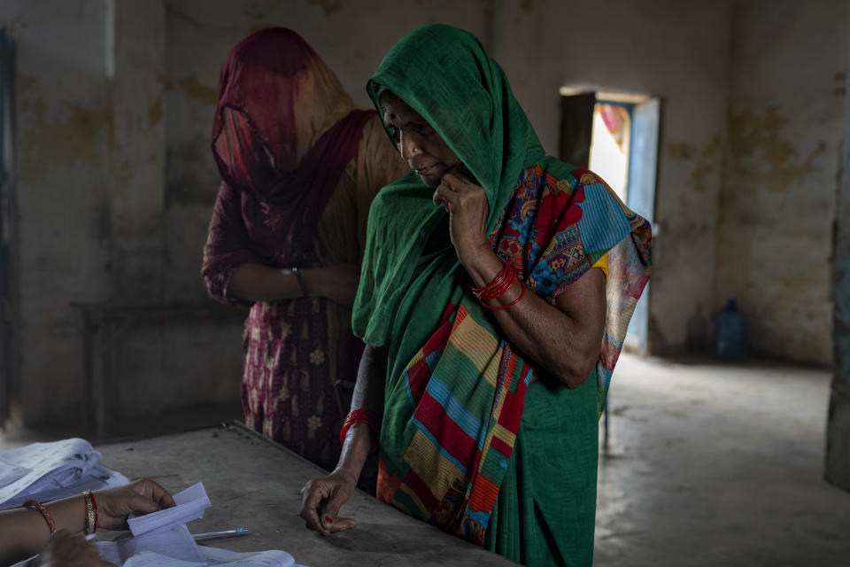 Voters wait as a polling official checks their names before allowing them to cast their vote during the third round of voting in the six-week-long general election in Agra, Uttar Pradesh, India, Tuesday, May 7, 2024. (AP Photo/Altaf Qadri)