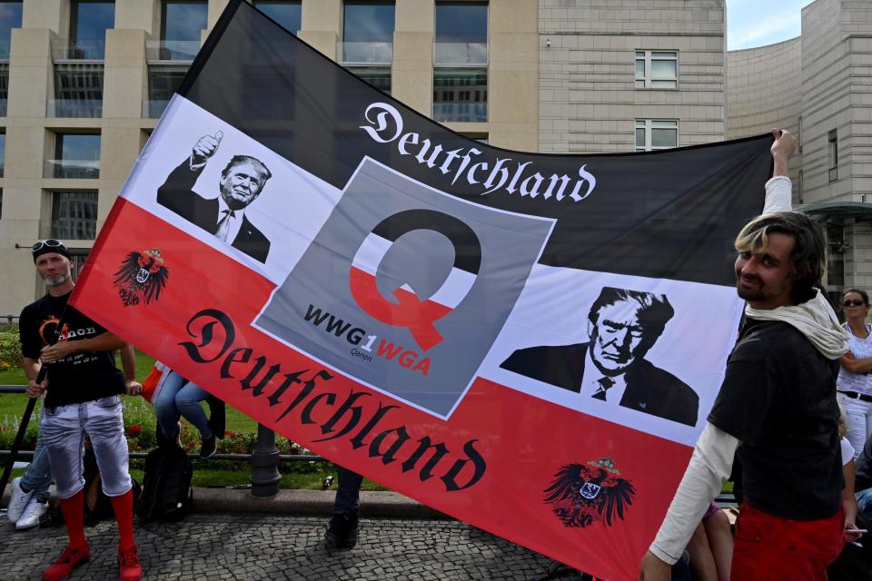 Protesters waves a flag featuring US President Donald Trump during a demonstration called by far-right and COVID-19 deniers to protest against restrictions related to the new coronavirus pandemic, on August 29, 2020 in Berlin. (Photo by John MACDOUGALL / AFP) (Photo by JOHN MACDOUGALL/AFP via Getty Images) / Credit: JOHN MACDOUGALL