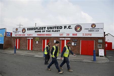 Workers walk past the Ebbsfleet United football ground in Ebbsfleet, southern England March 27, 2014. Under a new government-backed plan, more than 20,000 new homes will be built in Ebbsfleet, 20 miles east of London and just 17 minutes from the centre of the capital on a high-speed rail line. Picture taken on March 27, 2014. To match Analysis BRITAIN-HOUSING/ REUTERS/Stefan Wermuth