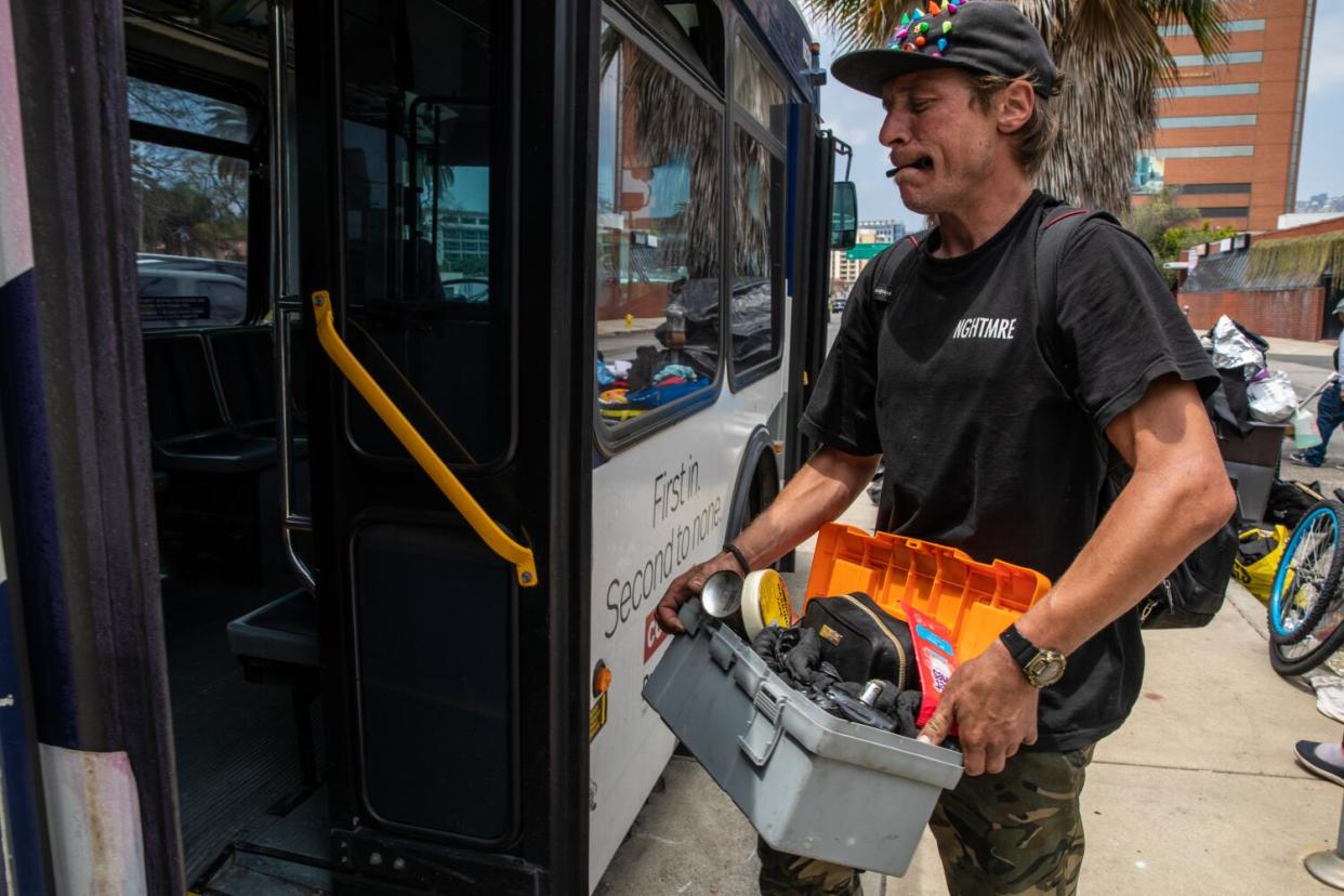 A man carries his belongings onto a bus