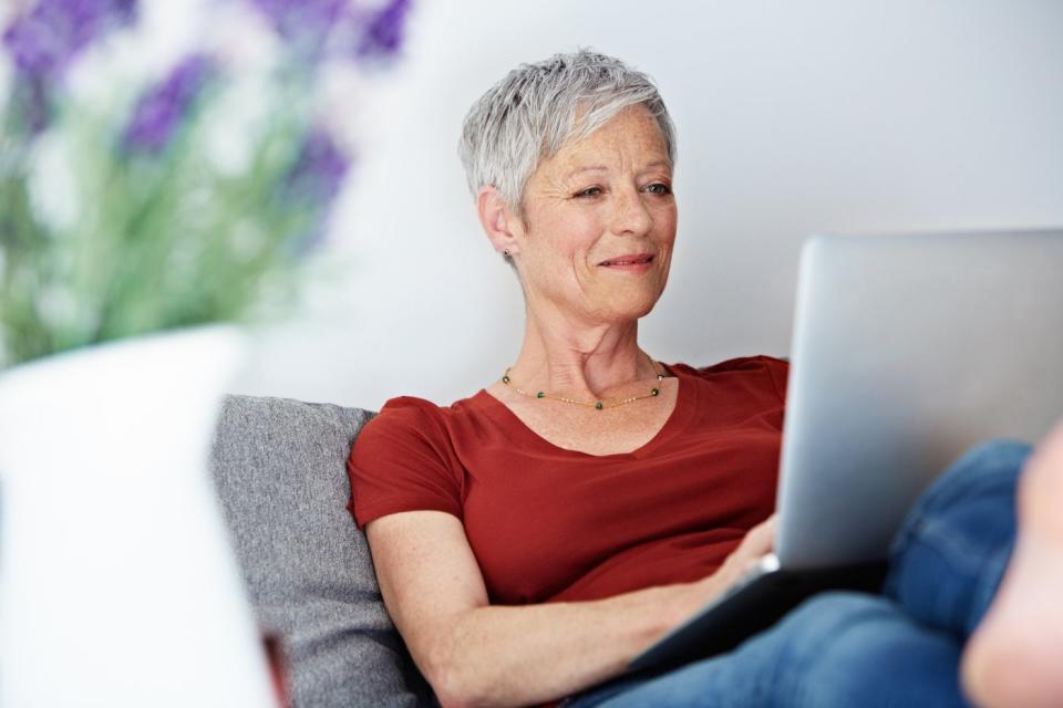 Smiling person looking at laptop.