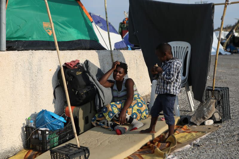 A woman sits next to a makeshift tent as refugees and migrants from the destroyed Moria are sheltered near a new temporary camp, on the island of Lesbos