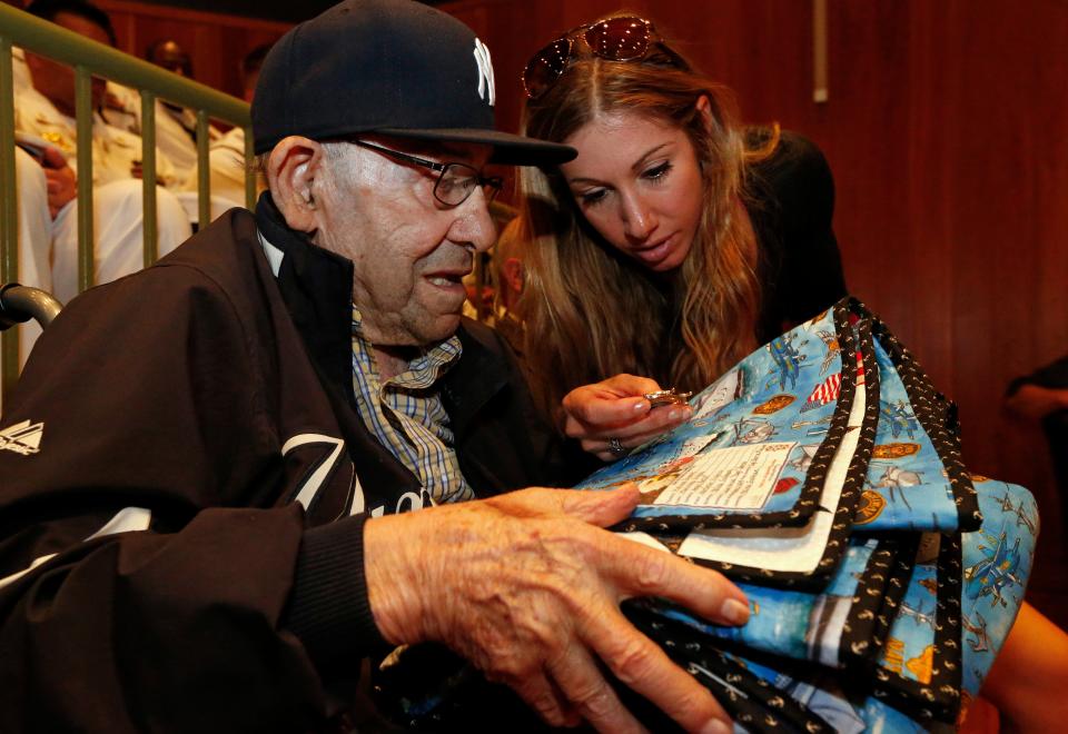 Baseball Hall of Famer Yogi Berra and his granddaughter Lindsay Berra look at a quilt and medal that was presented to him by members of the U.S. Navy during a D-Day presentation at the Yogi Berra Museum in Montclair, N.J., on Friday, June 6, 2014. Berra had served in the navy 70 years before as part of the D-Day invasion. (AP Photo/Rich Schultz)