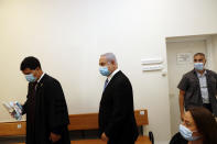 Israeli Prime Minister Benjamin Netanyahu, center, wearing a face mask in line with public health restrictions due to the coronavirus pandemic, enters the court room with his lawyer as his corruption trial opens at the Jerusalem District Court, Sunday, May 24, 2020. He is the country’s first sitting prime minister ever to go on trial, facing charges of fraud, breach of trust, and accepting bribes in a series of corruption cases stemming from ties to wealthy friends. (Ronen Zvulun/ Pool Photo via AP)