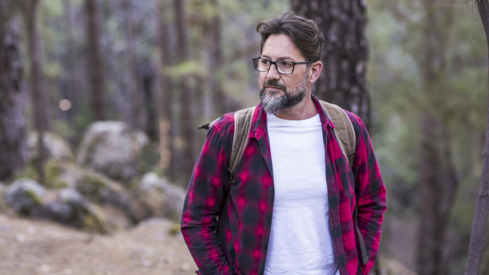 Hiker wearing a flannel shirt and cotton T shirt in a forest