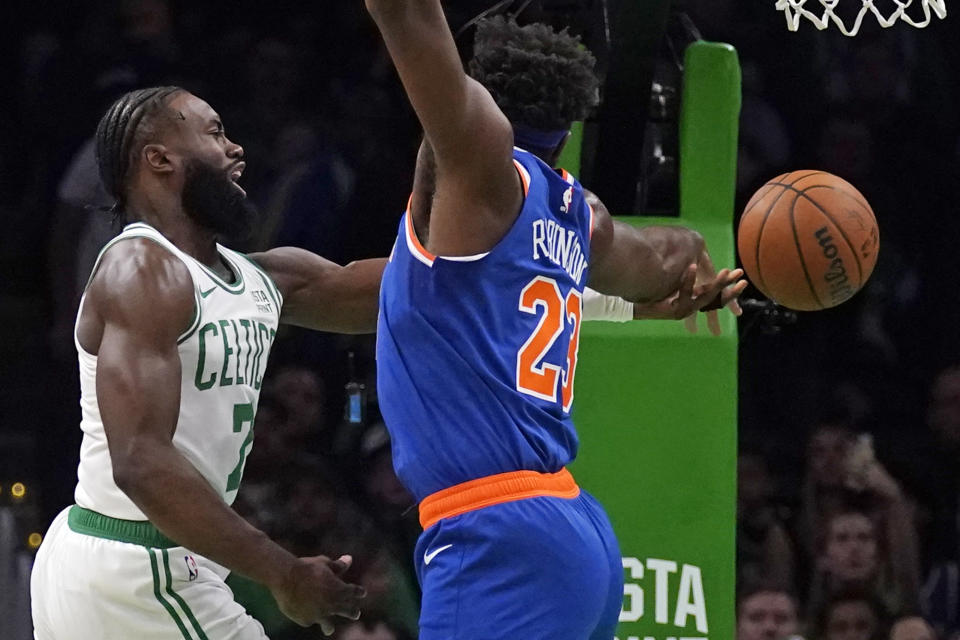 Boston Celtics guard Jaylen Brown, left, tries to pass the ball against New York Knicks center Mitchell Robinson, right, during the first half of a preseason NBA basketball game, Tuesday, Oct. 17, 2023, in Boston. (AP Photo/Charles Krupa)