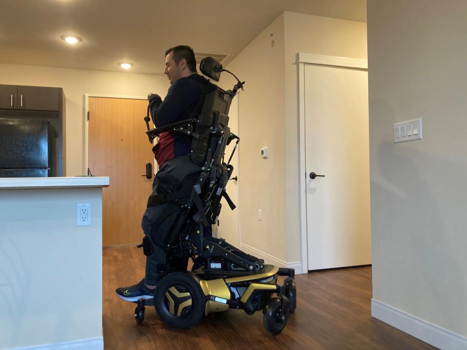 Arif Faizi, 34, demonstrates the standing function of his motorized wheelchair, which helps relieve painful muscle spasms in his legs.