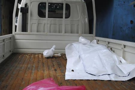 The body of a victim of Ebola virus is seen covered with a sheet at the back of a truck after health workers collected it in Monrovia, September 13, 2014. REUTERS/James Giahyue