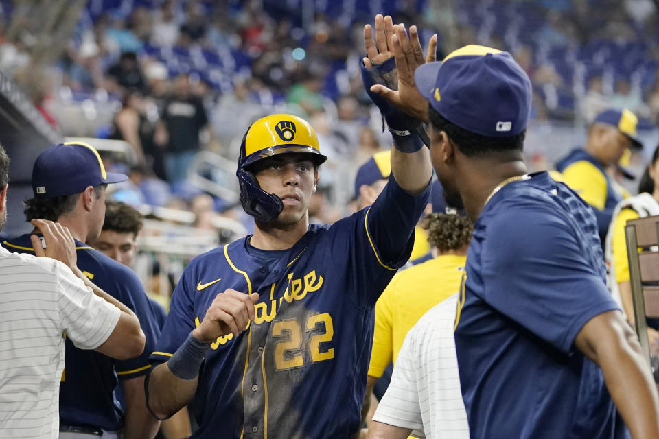 Milwaukee Brewers' Christian Yelich (22) is congratulated after scoring on a single by Omar Narvaez during the fifth inning of a baseball game against the Miami Marlins, Sunday, May 15, 2022, in Miami. (AP Photo/Lynne Sladky)