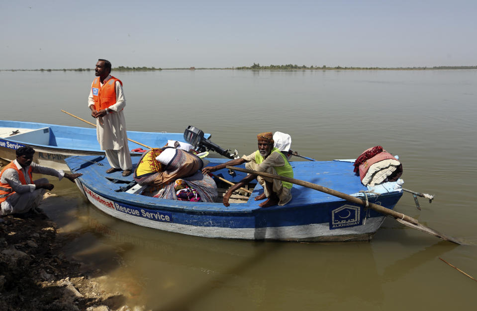 Victims of the unprecedented flooding from monsoon rains receive relief aid, organized by the Islamic group Jamaat-e-Islami Pakistan, in Sukkur, Pakistan, Sunday, Sept. 4, 2022. Officials warned Sunday that more flooding was expected as Lake Manchar in southern Pakistan swelled from monsoon rains that began in mid-June and have killed nearly 1,300 people. (AP Photo/Fareed Khan)